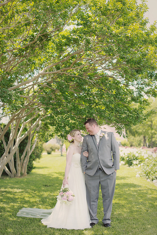 Smiling wedding couple under a tree in outdoor setting