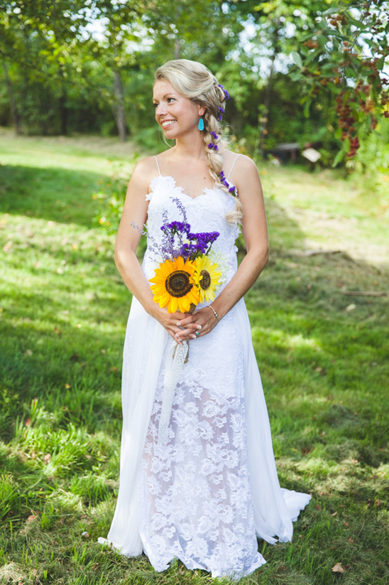 Boho bride holding sunflower bouquet on wedding day