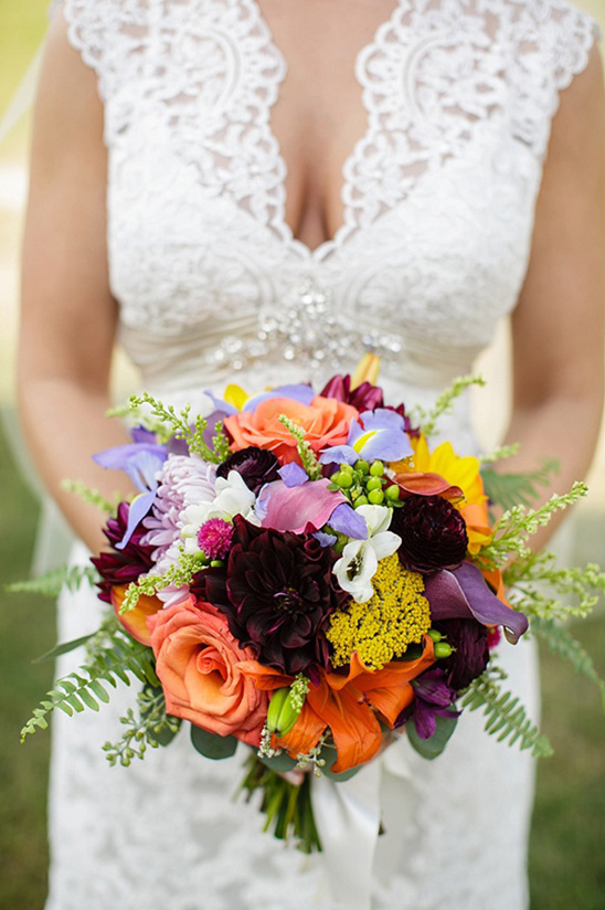 Vibrant wedding bouquet held by bride in lace dress
