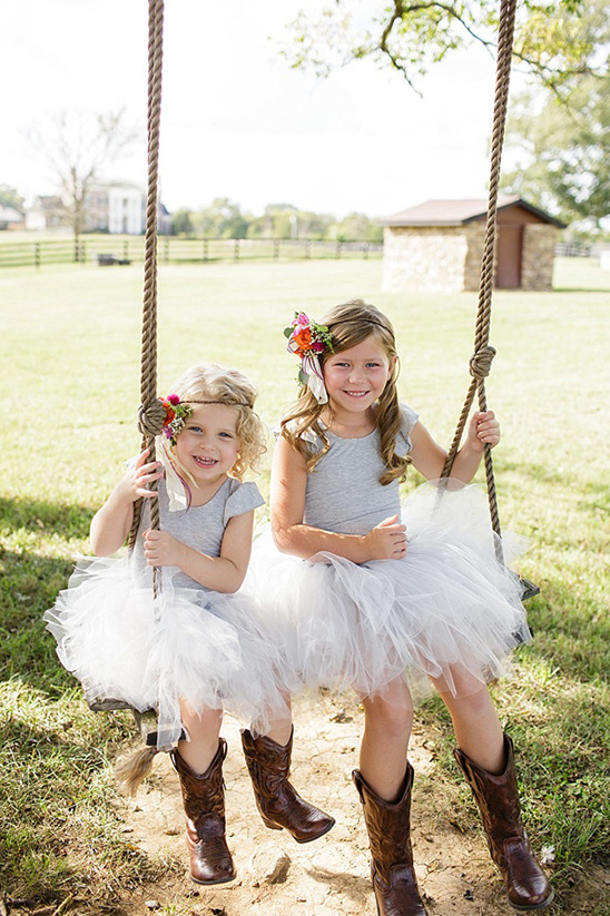 Cute girls in tutus cowboy boots outdoor rope swing