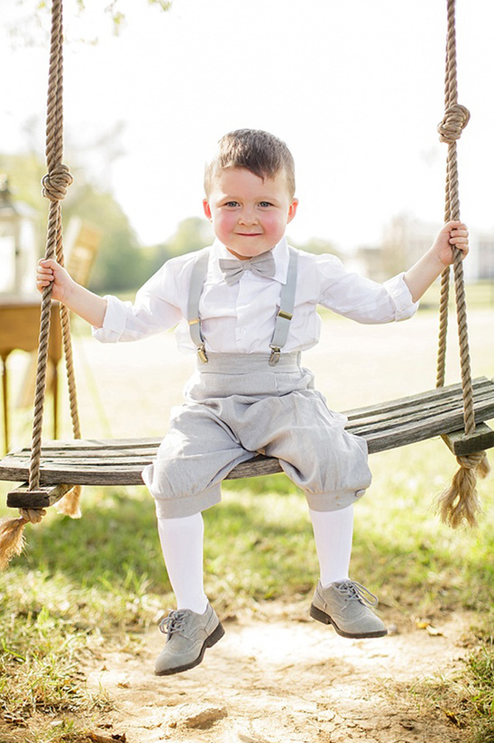 Happy young boy in formal wear sits on wooden swing