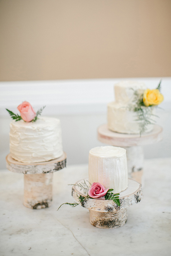 Rustic mini wedding cakes with flowers on wooden stands