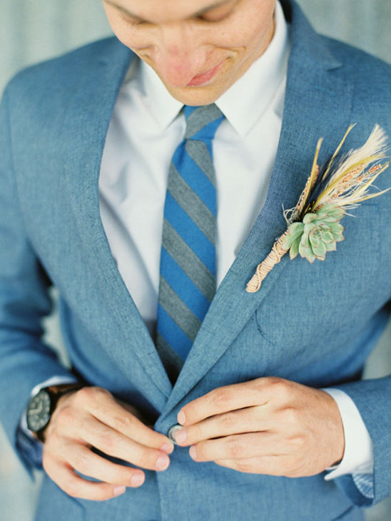 Groom buttons blue suit with succulent boutonniere