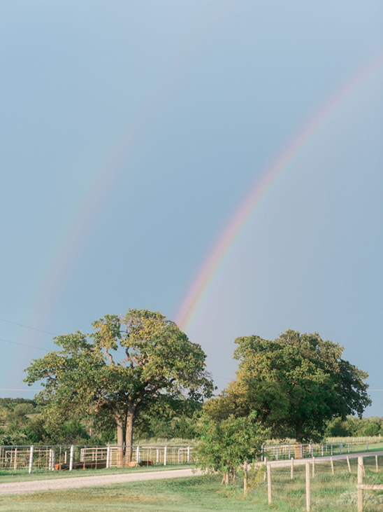 Double rainbow over lush green trees on a rural farm