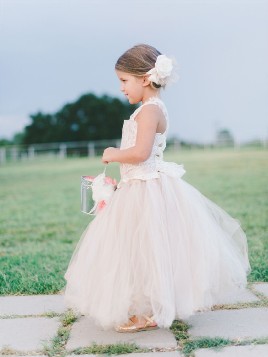 Cute flower girl in tulle dress at outdoor wedding