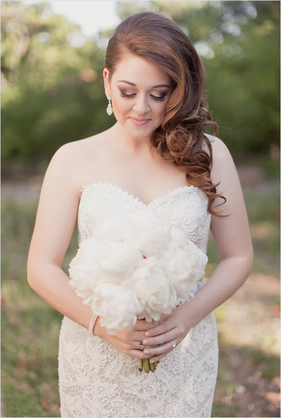 Elegant bride with beautiful hairstyle holding white flower bouquet