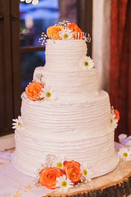 White tiered wedding cake with orange rose decorations