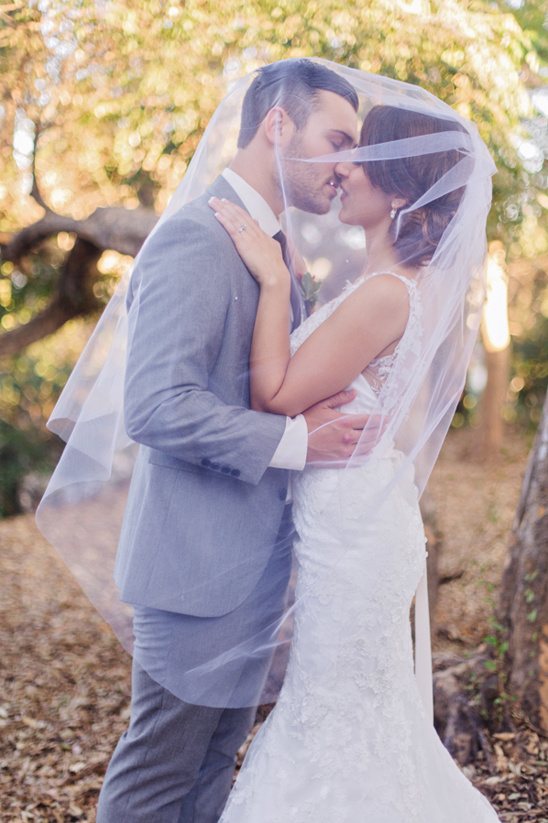 Bride and groom share a kiss under her wedding veil
