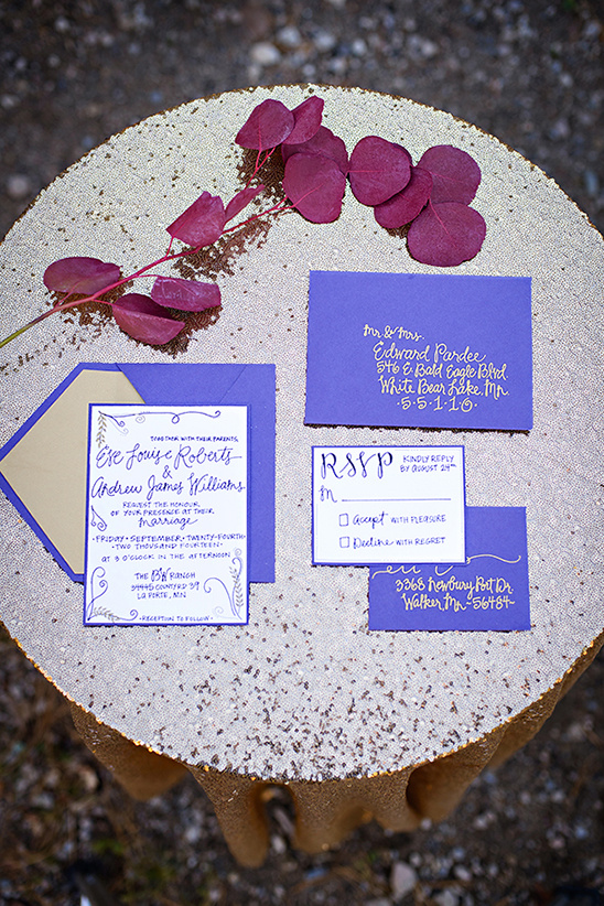 Elegant purple wedding invitation suite on gold table