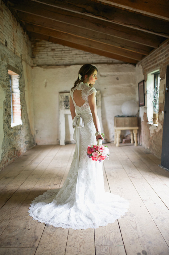 Bride in lace wedding dress holding bouquet indoors