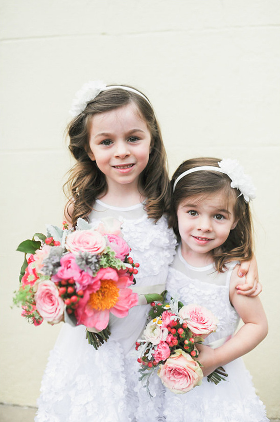 Two cute flower girls with bouquets in white dresses