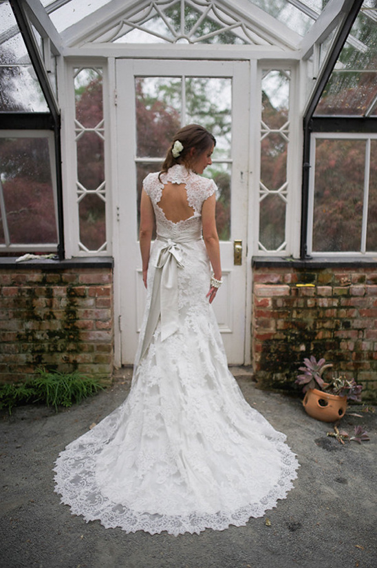 Bride in lace wedding dress at greenhouse entrance