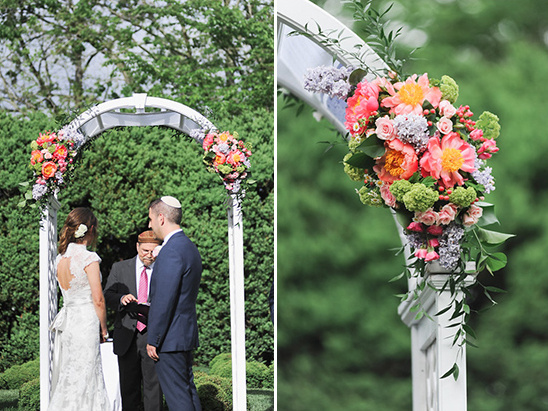 Wedding ceremony under floral archway chuppah outdoors