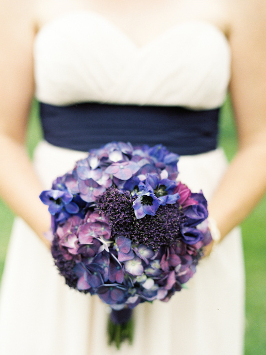 Elegant bride holds purple hydrangea and anemone bouquet