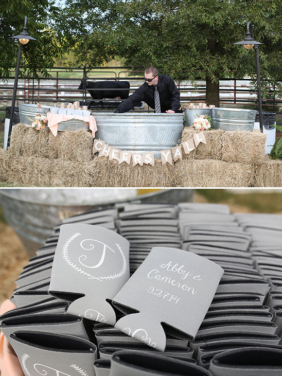 Rustic outdoor wedding bar with Cheers Yall banner and custom koozies