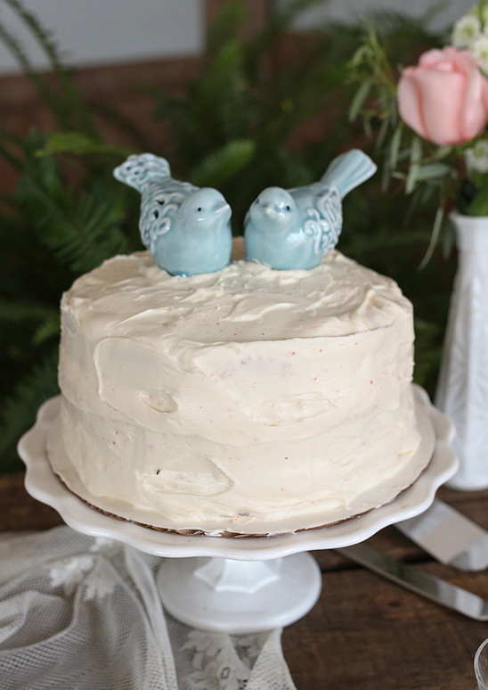 Delicious cake with blue bird toppers on a white cake stand