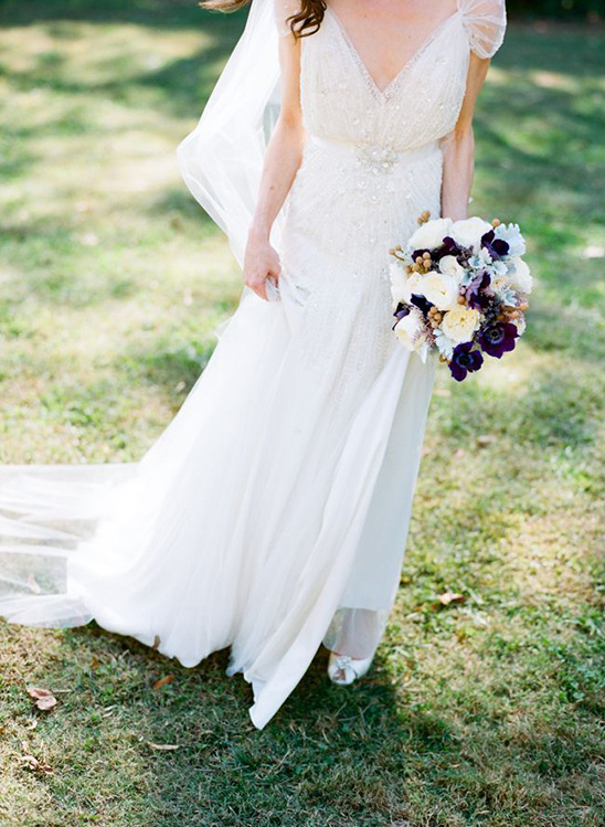 Bride in beaded wedding dress holding flower bouquet