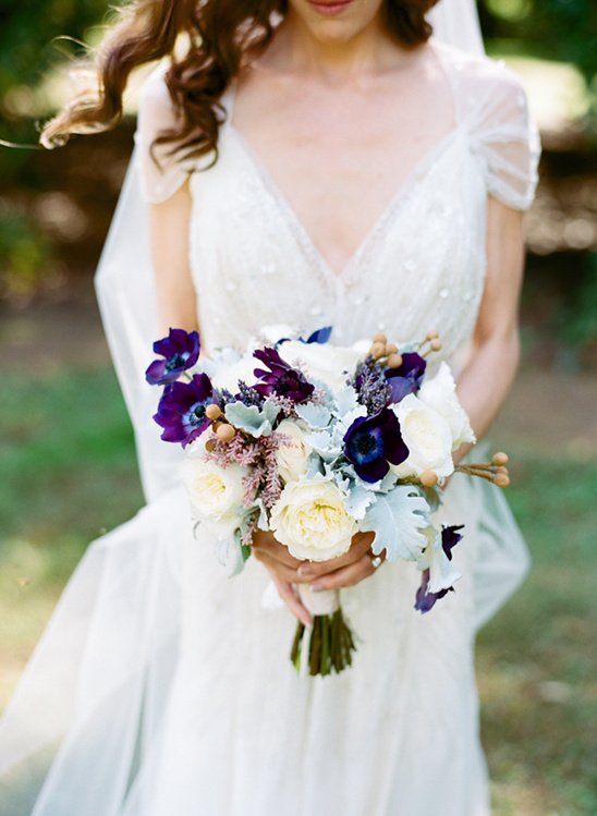 Elegant bride holds purple and white wedding bouquet