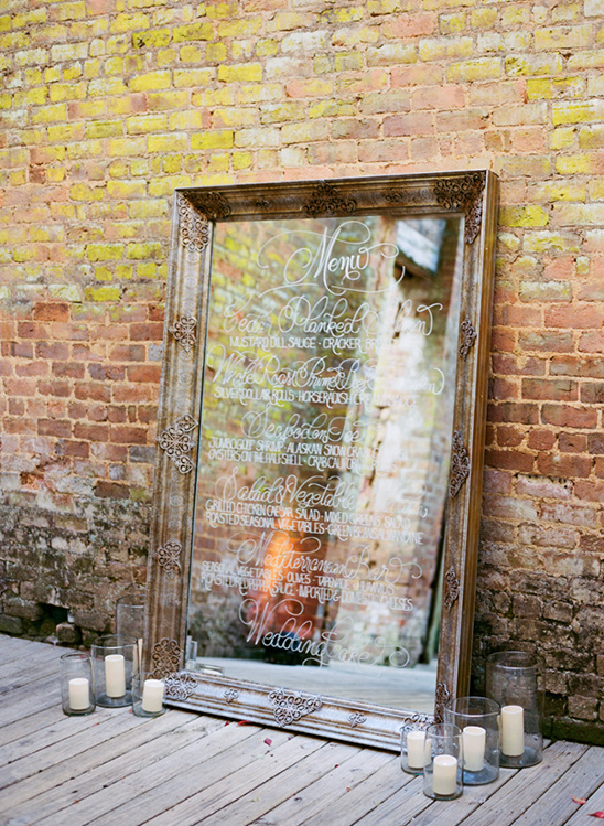 Rustic wedding menu on mirror decor with candles brick wall