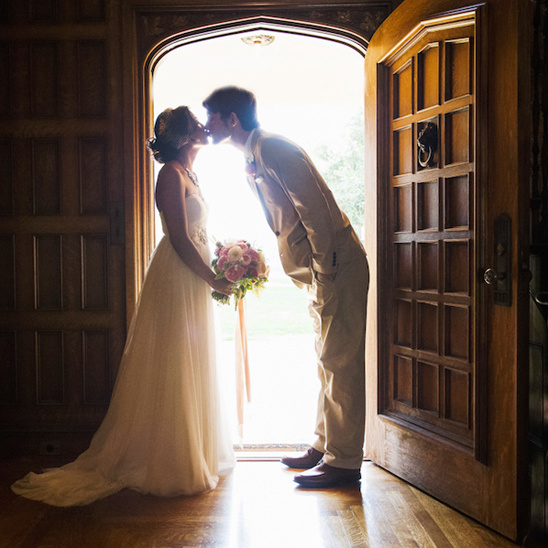 Newlyweds share a tender kiss at their wedding doorway