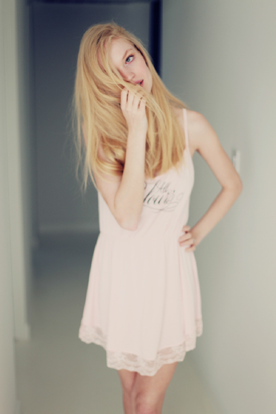 Blond woman in pink dress, playing with hair
