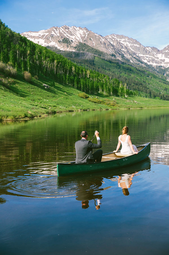 Bride and groom canoe ride on mountain lake wedding