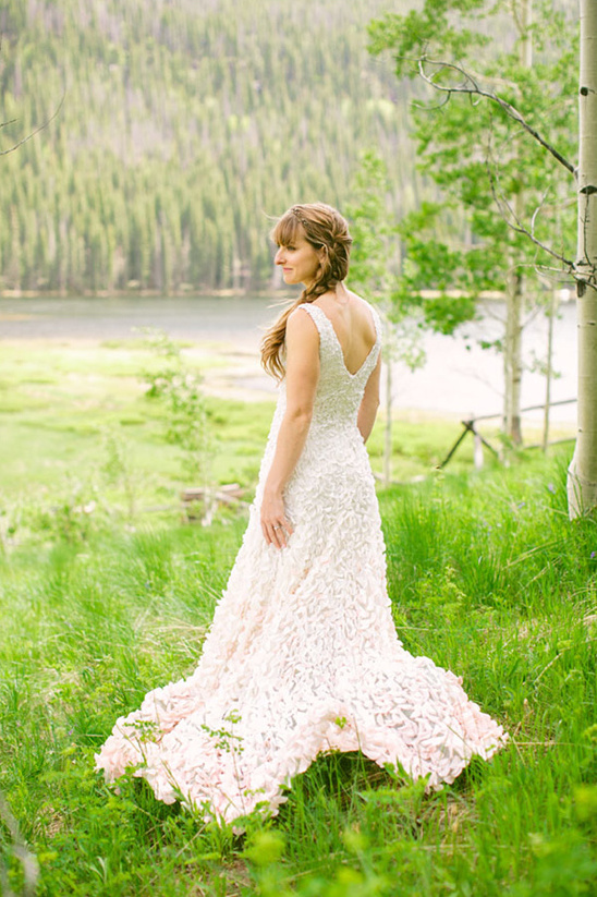 Bride in elegant gown poses in a lush green meadow