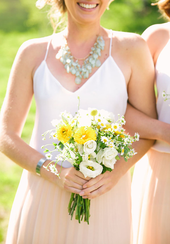Bridesmaid holds a yellow and white wildflower bouquet