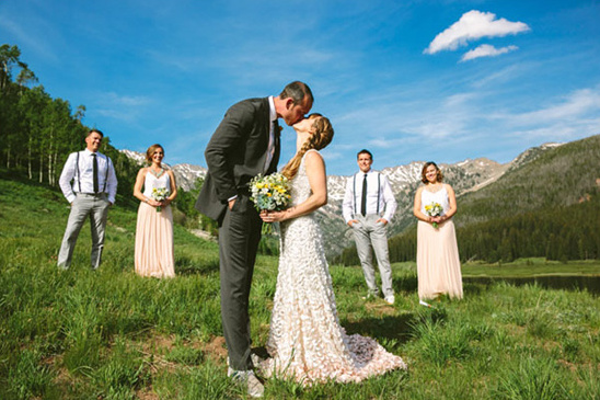 Bride and groom kiss during outdoor mountain wedding