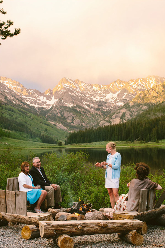 Group gathered around a campfire with scenic mountains in the background