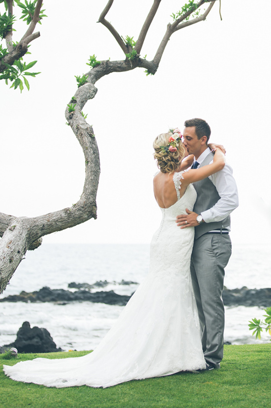 Newlyweds sharing a kiss by the ocean on their wedding day