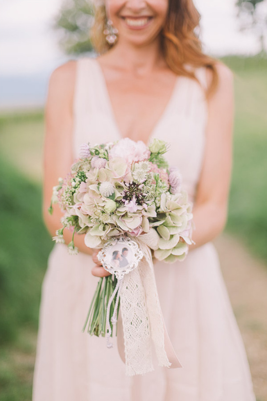 Bride smiles holding her wedding bouquet with photo charm