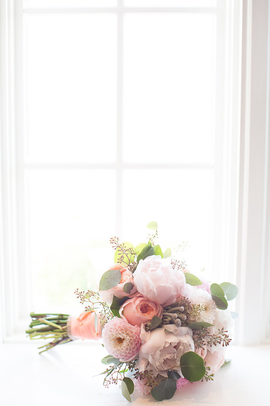 Elegant bridal bouquet with peonies resting on a white surface