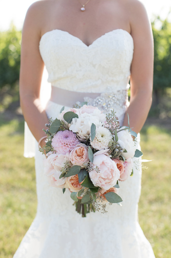 Bride in white lace dress holds a stunning wedding bouquet
