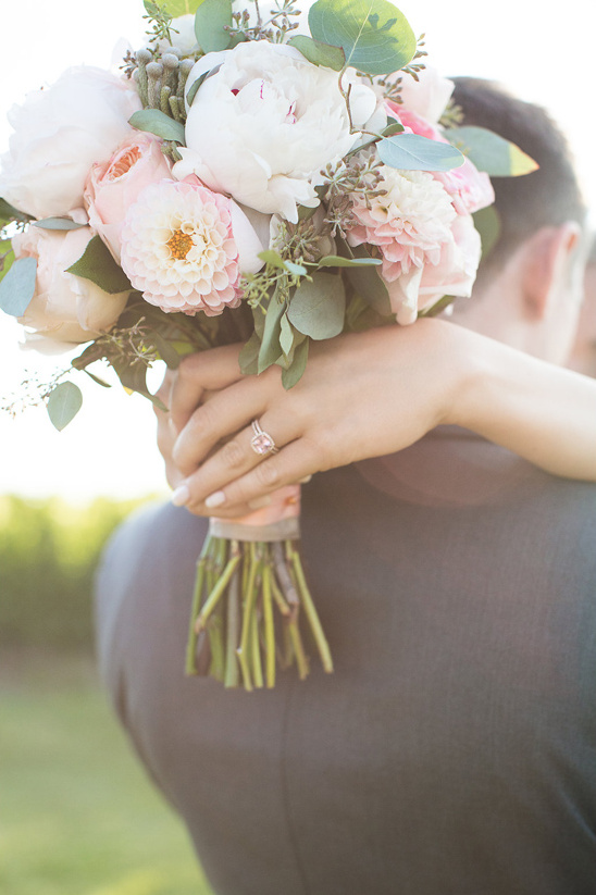 Bride holding a bouquet hugging groom at their wedding
