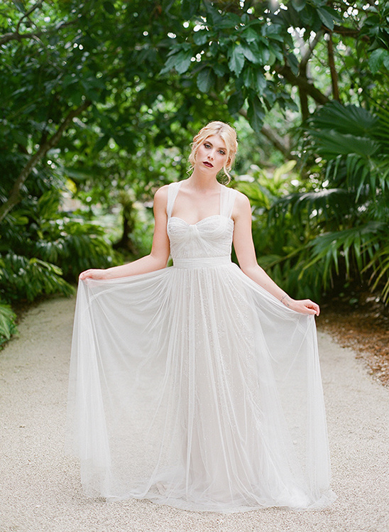 Elegant bride in a white dress posing in a lush garden