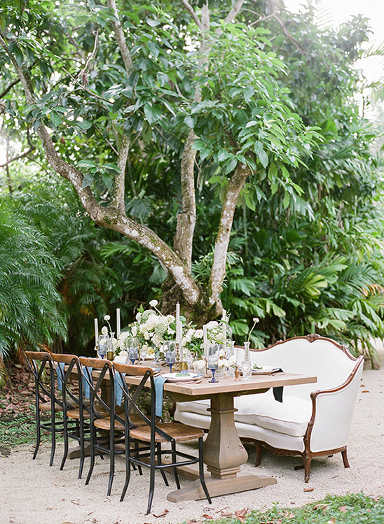 Elegant outdoor wedding table setting under a lush green tree