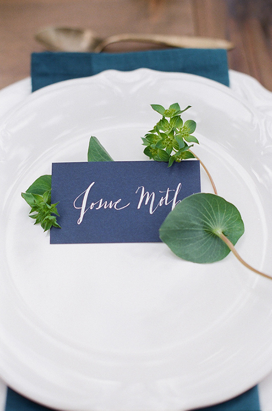 Elegant place setting with name card and greenery for a wedding