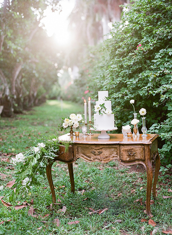 Romantic outdoor wedding cake on vintage desk with flowers