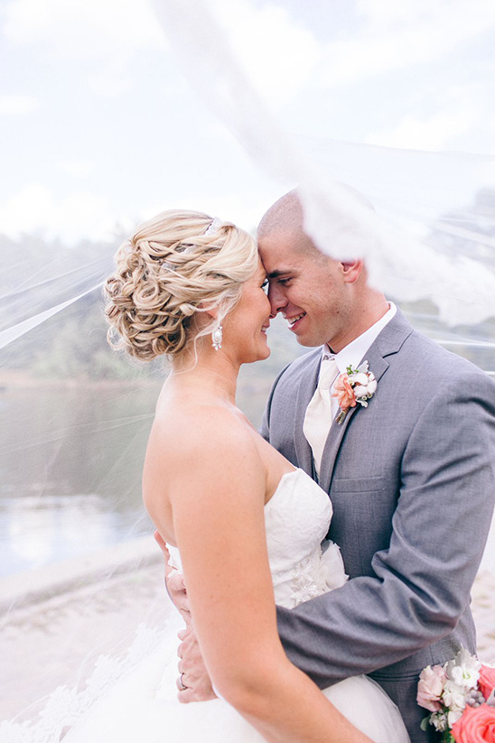 Happy bride and groom embracing on their wedding day under veil