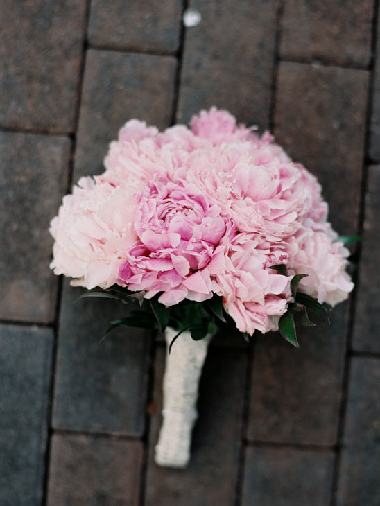 Beautiful pink peony bridal bouquet on a brick patio