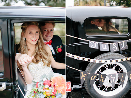 Bride and groom smiling in car, with Just Married sign and kiss
