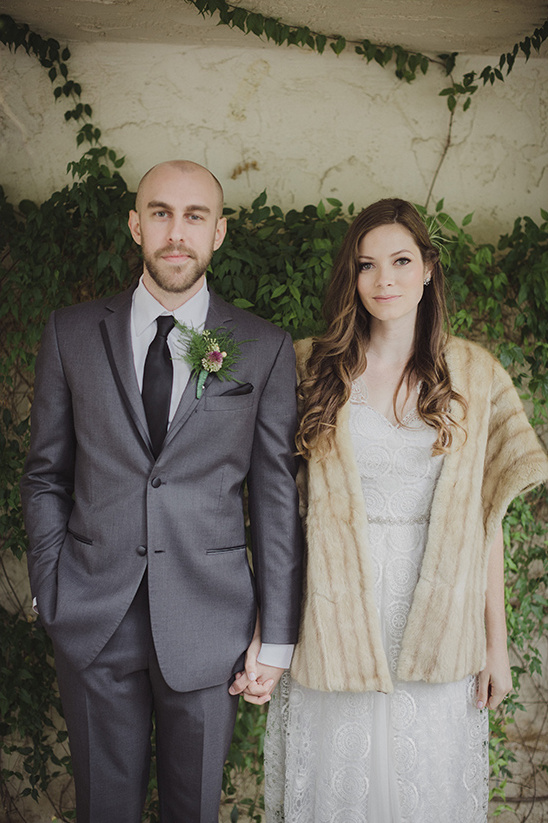 Newlyweds holding hands in front of a green wall, wedding portrait