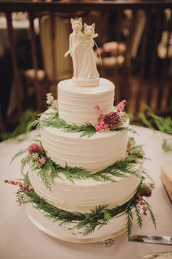 Three-tiered wedding cake with cat topper and floral decor