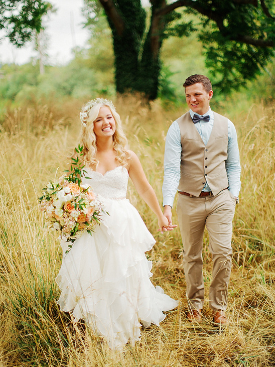 Happy couple on their wedding day walking in a field