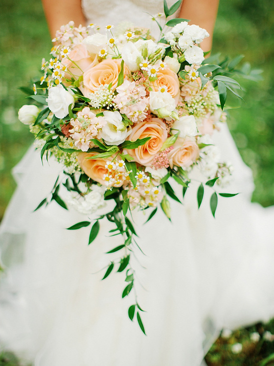 Bride holding a beautiful cascading bouquet of peach roses