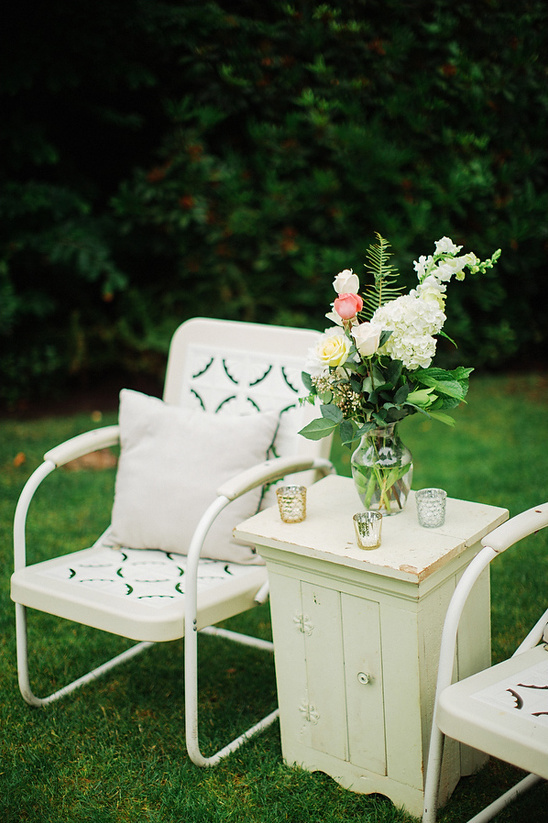 White chairs with a vase of flowers in a backyard setting