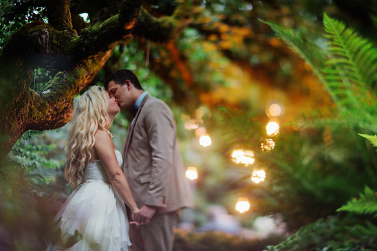 Romantic couple kissing under a mossy tree in a whimsical forest