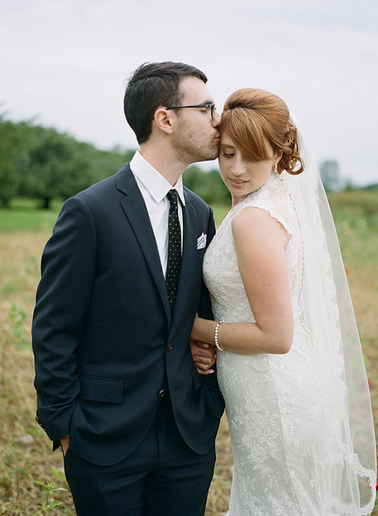 Groom kisses his bride on the forehead during their wedding day