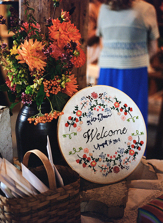 Welcome sign with floral embroidery and flower vase